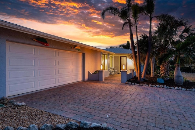 garage at dusk featuring decorative driveway