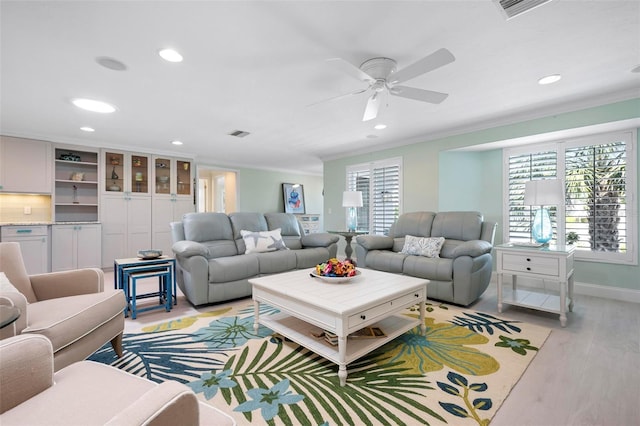 living area featuring light wood finished floors, plenty of natural light, and ornamental molding