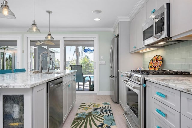 kitchen featuring light wood finished floors, ornamental molding, decorative backsplash, a sink, and appliances with stainless steel finishes