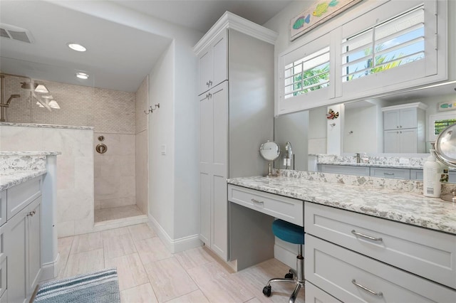 bathroom with visible vents, baseboards, walk in shower, and vanity