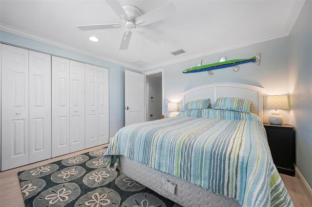 bedroom with visible vents, ornamental molding, wood finished floors, a closet, and a ceiling fan