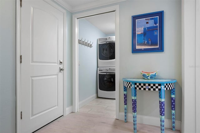 laundry area with laundry area, wood finished floors, baseboards, and stacked washing maching and dryer