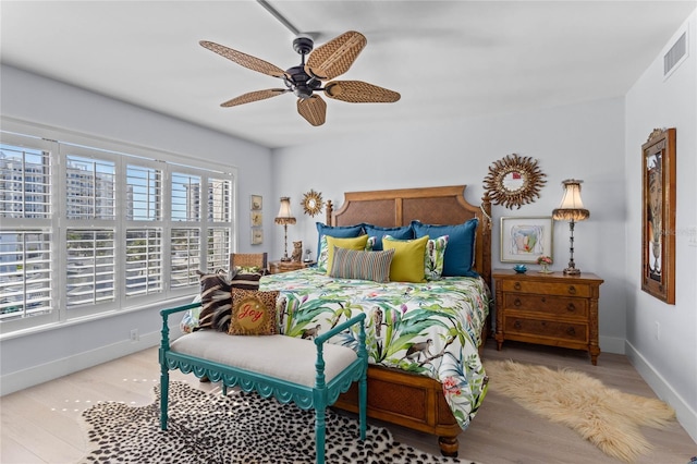 bedroom with a ceiling fan, wood finished floors, visible vents, and baseboards