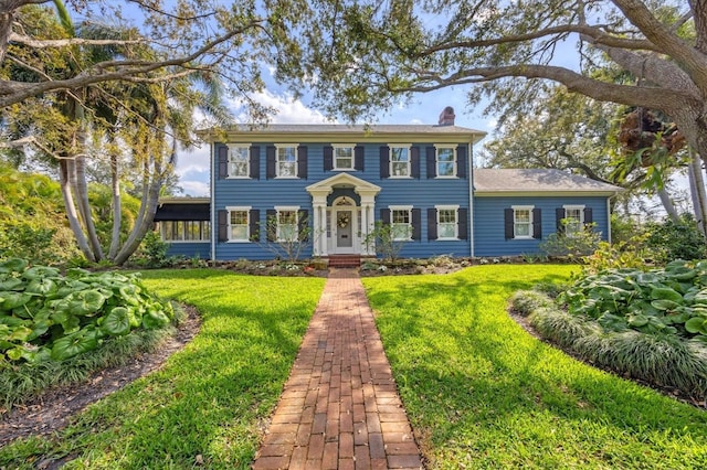 colonial-style house featuring a front yard and a chimney