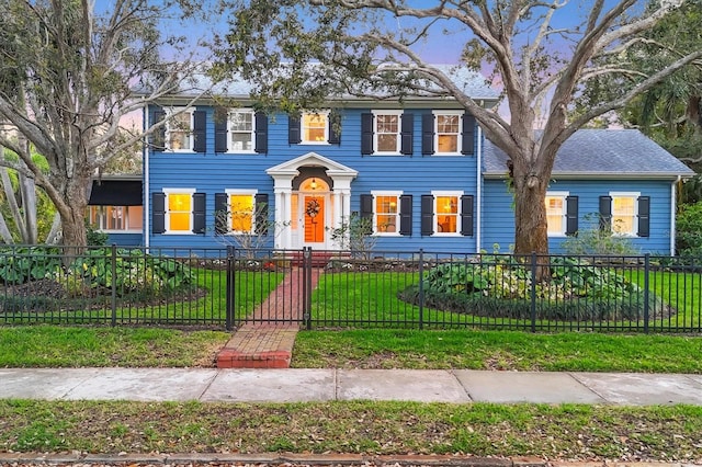 colonial home featuring a front lawn and a fenced front yard