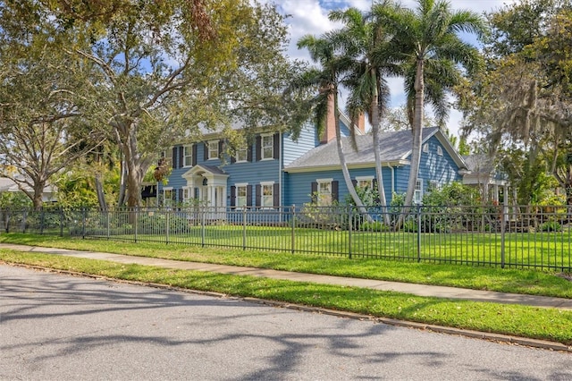 colonial house with a front lawn and a fenced front yard