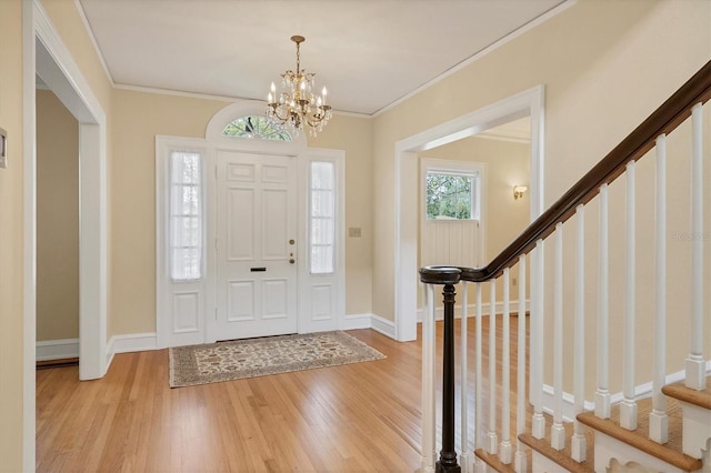 foyer entrance featuring ornamental molding, baseboards, light wood finished floors, and stairs