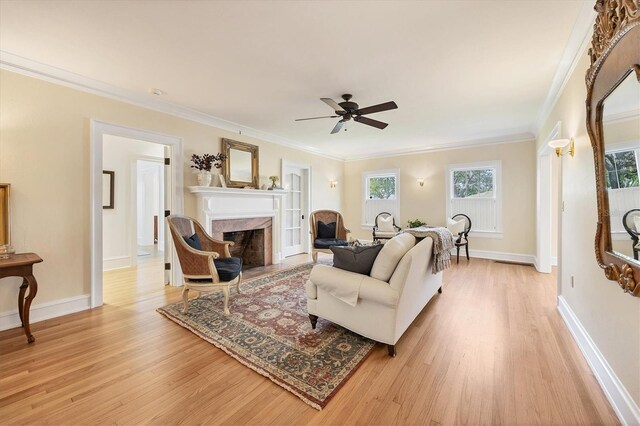 living room featuring light wood finished floors, a wealth of natural light, crown molding, and a high end fireplace