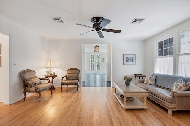 living area featuring light wood-style floors, visible vents, ceiling fan, and baseboards