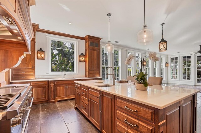 kitchen with a sink, light countertops, double oven range, brown cabinets, and an island with sink