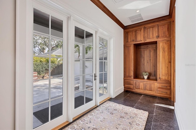 doorway featuring crown molding, stone tile floors, visible vents, and baseboards