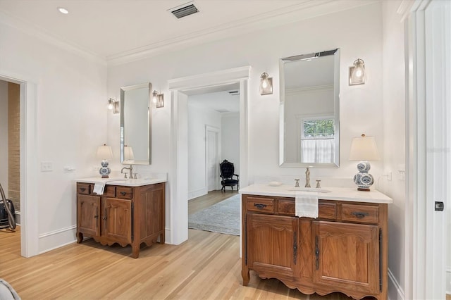 full bathroom with two vanities, visible vents, crown molding, and wood finished floors