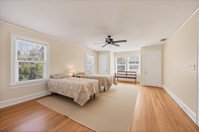 bedroom with light wood-style floors, visible vents, and crown molding