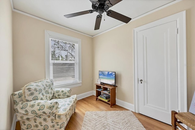 living area with ceiling fan, ornamental molding, light wood-type flooring, and baseboards