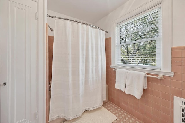 full bath featuring curtained shower, tile walls, and wainscoting