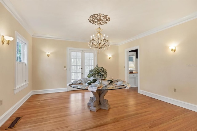 dining space with ornamental molding, light wood-style flooring, plenty of natural light, and visible vents