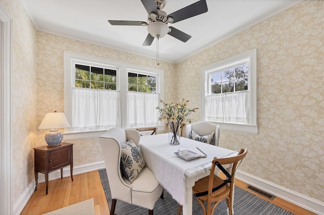 dining area with light wood-type flooring, wallpapered walls, baseboards, and visible vents