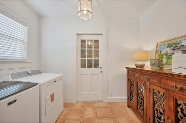 washroom with laundry area, light tile patterned flooring, washing machine and clothes dryer, and baseboards