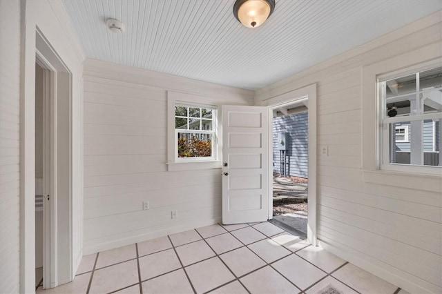 interior space with light tile patterned floors and wood walls