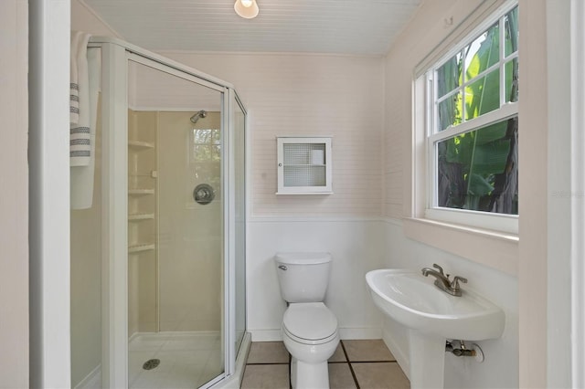 full bath featuring toilet, a stall shower, tile patterned flooring, and baseboards