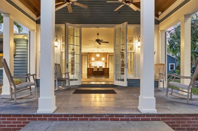 entrance to property featuring french doors, brick siding, and ceiling fan