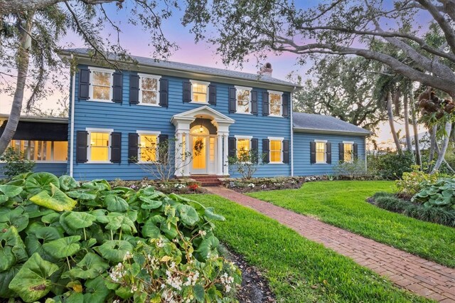 colonial-style house with a front yard and a chimney