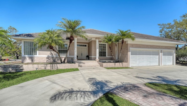 view of front of home featuring stucco siding, a garage, and driveway