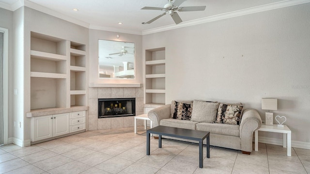 living room featuring built in shelves, baseboards, light tile patterned flooring, a tile fireplace, and crown molding