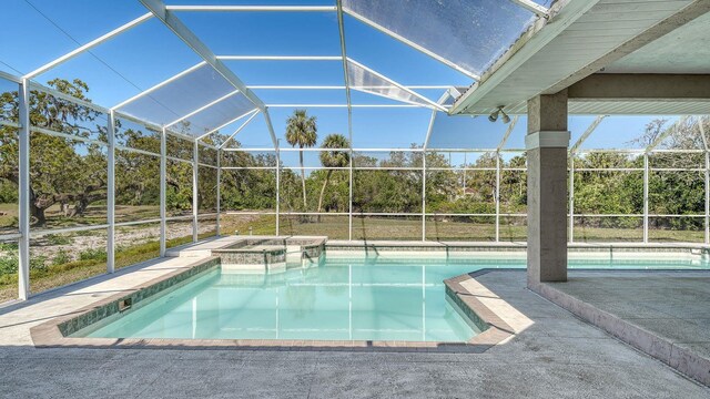 pool with a lanai, a patio area, and an in ground hot tub