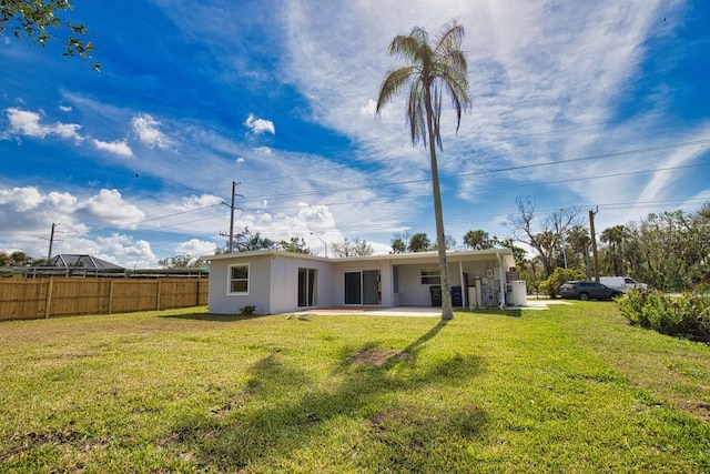 rear view of property featuring a lawn, a patio area, fence, and stucco siding