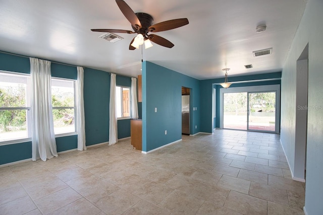 spare room featuring a wealth of natural light, visible vents, and baseboards