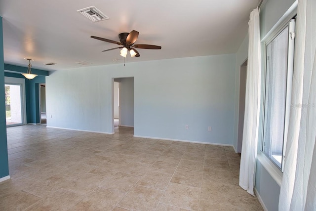 spare room with a ceiling fan, visible vents, and baseboards