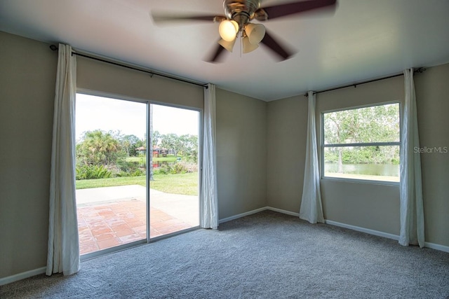 unfurnished room featuring a ceiling fan, carpet flooring, a wealth of natural light, and baseboards