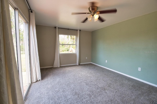 carpeted empty room with ceiling fan and baseboards