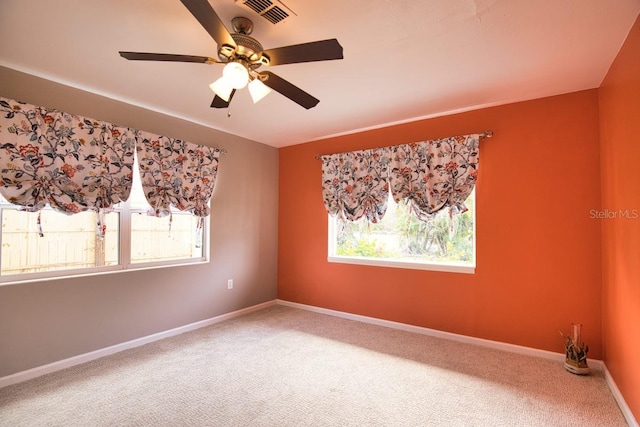 spare room with carpet, plenty of natural light, visible vents, and baseboards