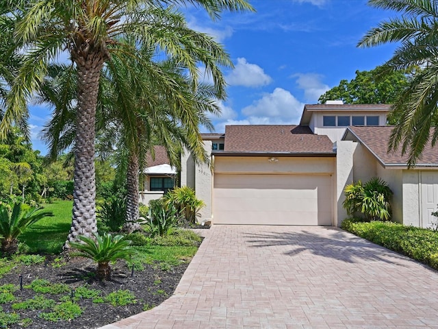 view of front of property featuring a garage, decorative driveway, and stucco siding