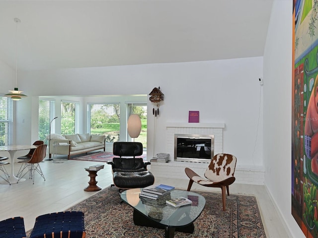 living room with a brick fireplace, baseboards, and wood finished floors