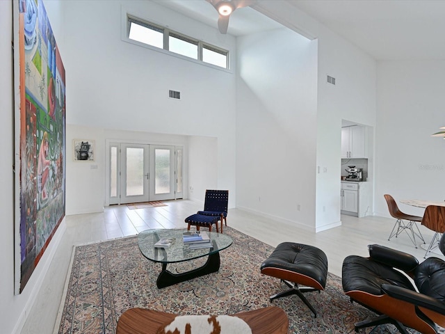 living room featuring light wood finished floors, french doors, plenty of natural light, and visible vents