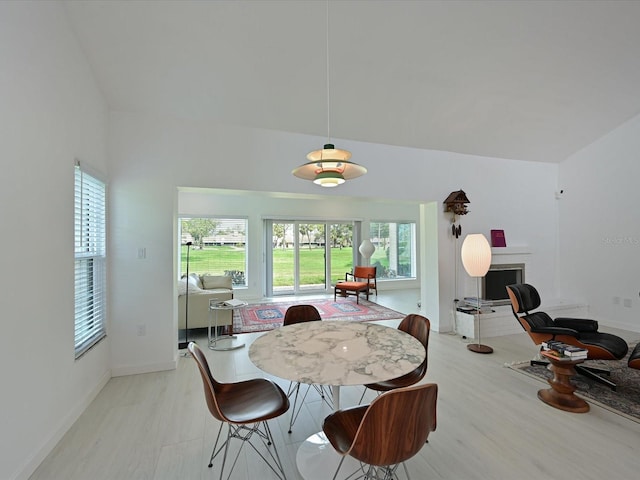 dining room featuring baseboards, a fireplace, and light wood-style floors