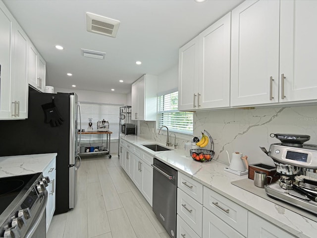 kitchen featuring white cabinetry, visible vents, stainless steel appliances, and a sink