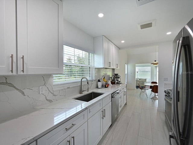 kitchen with tasteful backsplash, visible vents, appliances with stainless steel finishes, white cabinetry, and a sink