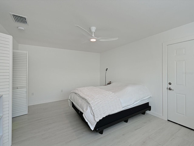 bedroom with ceiling fan, light wood-style flooring, visible vents, and baseboards