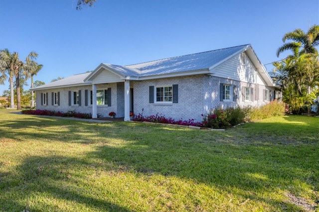 ranch-style home featuring metal roof, brick siding, and a front yard