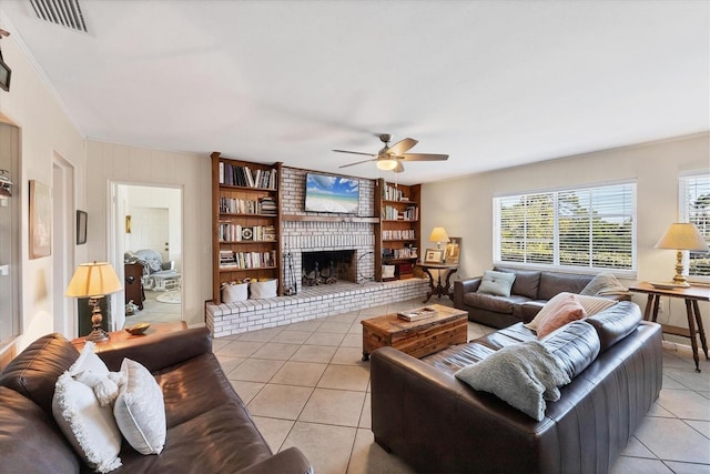 living room with visible vents, ornamental molding, light tile patterned floors, a brick fireplace, and ceiling fan