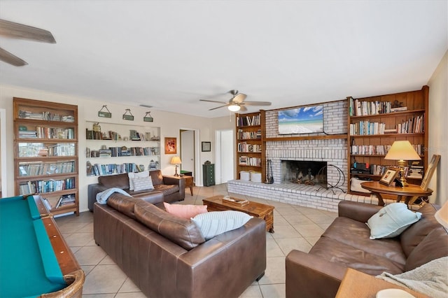 living area featuring built in shelves, light tile patterned floors, visible vents, ceiling fan, and a brick fireplace