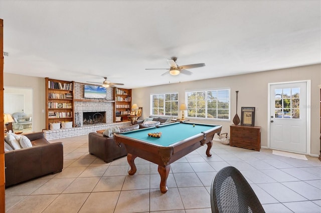 rec room featuring light tile patterned flooring, ceiling fan, a fireplace, and a wealth of natural light