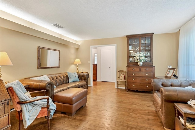 living room featuring visible vents, a textured ceiling, and light wood-style floors