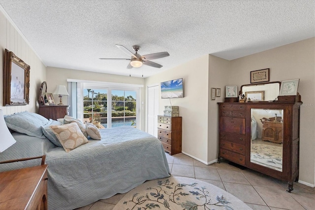 bedroom with light tile patterned floors, a ceiling fan, baseboards, access to exterior, and a textured ceiling