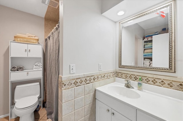 bathroom with vanity, a wainscoted wall, visible vents, tile walls, and toilet