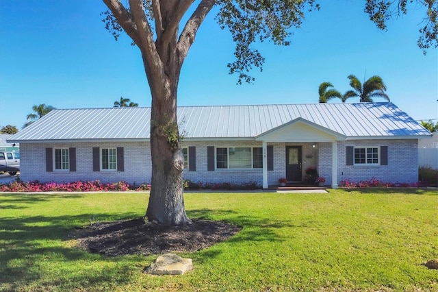 ranch-style home with brick siding, metal roof, and a front yard